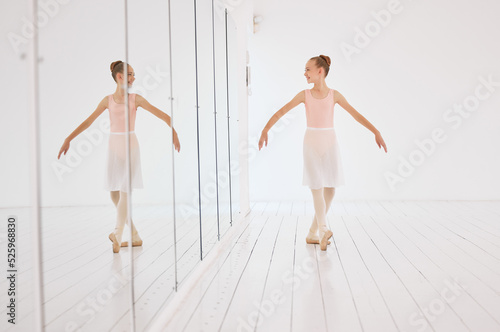 Fitness, exercise and the art of ballet, young dancer watching herself in a mirror. Happy, confident and learning to love dance and dancing the lifestyle. A ballerina girl training alone in a studio.