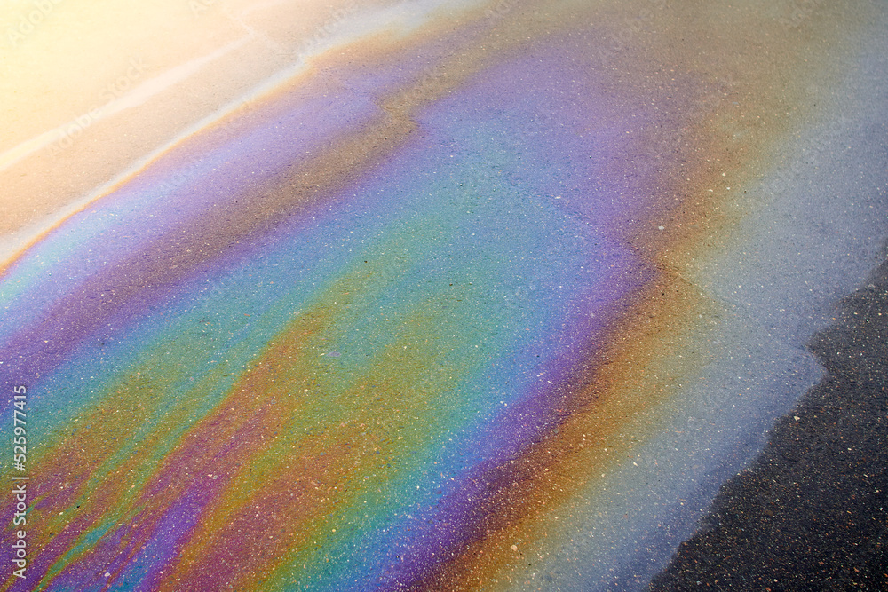 Obraz premium Oil stain on the asphalt, rainbow-shaped colored gasoline stains on an asphalt road as a texture or background