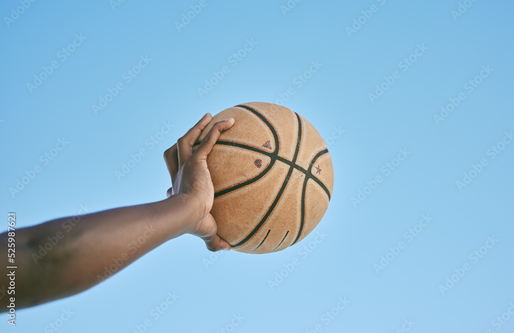 Basketball, active and sports man hand holding ball showing victory, power or athletic fitness from below with blue sky background. Player, black man or athlete arm practicing for professional league Basketball, active and sports man hand holding ball showing victory, power or athletic fitness from below with blue sky background. Player, black man or athlete arm practicing for professional league