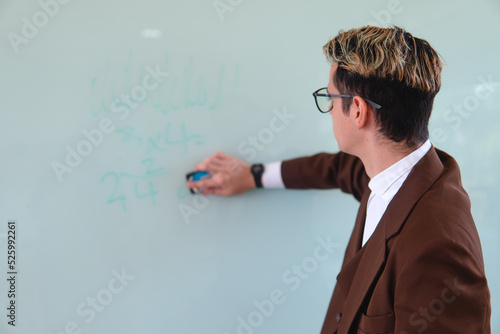 Teacher erasing the blackboard. Caucasian teacher, blond and smartly dressed in a brown suit and wearing glasses. High quality photo photo