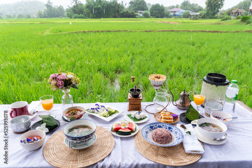Breakfast, porridge, fruit salad, not dessert and drip coffee are placed on the terrace overlooking the rice fields.