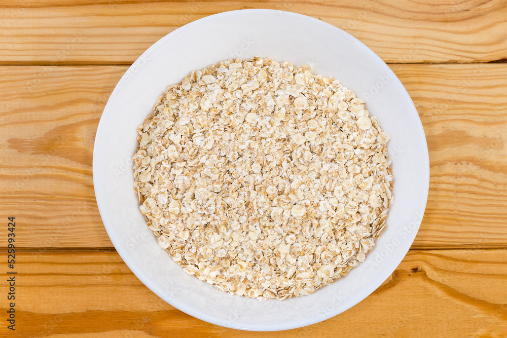 Raw rolled oats in bowl on rustic table, top view Raw rolled oats in bowl on rustic table, top view
