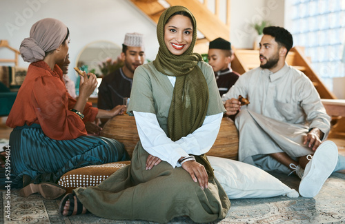 A happy Muslim woman sitting, with family and celebration of culture during Ramadan. A modern Islamic lady with a smile, beauty and in a hijab to celebrate holiday and eat together and home for Eid