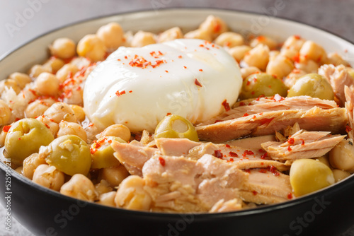 Traditional Tunisian chickpea soup served for breakfast Lablabi with a poached egg and tuna closeup in the bowl on the table. Horizontal photo