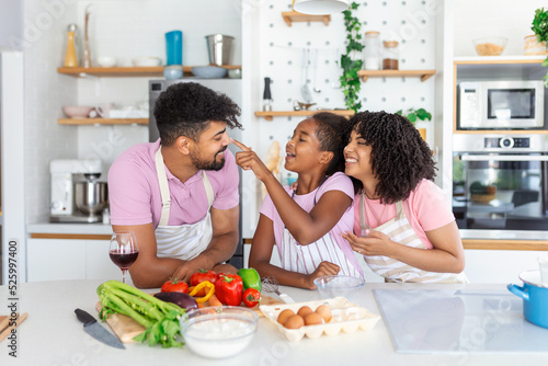 Overjoyed young family with Daughter have fun cooking baking pastry or pie at home together  happy smiling parents enjoy weekend play with child doing bakery cooking in kitchen
