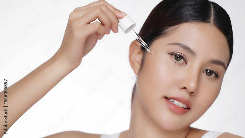 Young Asian beautiful woman dropping serum on face. Woman putting anti-ageing moisturizing serum to under eye area. Beauty therapy concept.