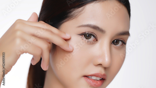Closeup portrait Asian women with face care gently massaging applying moisturizing cream on cheek and under eye.