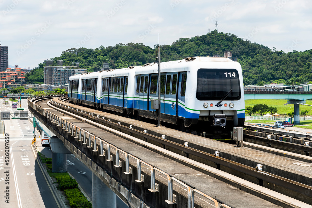 Fototapeta premium Wenhu or Brown line of Taipei MRT in Taiwan. View of a train running on the elevated track of the Taipei subway system under a clear blue sky.