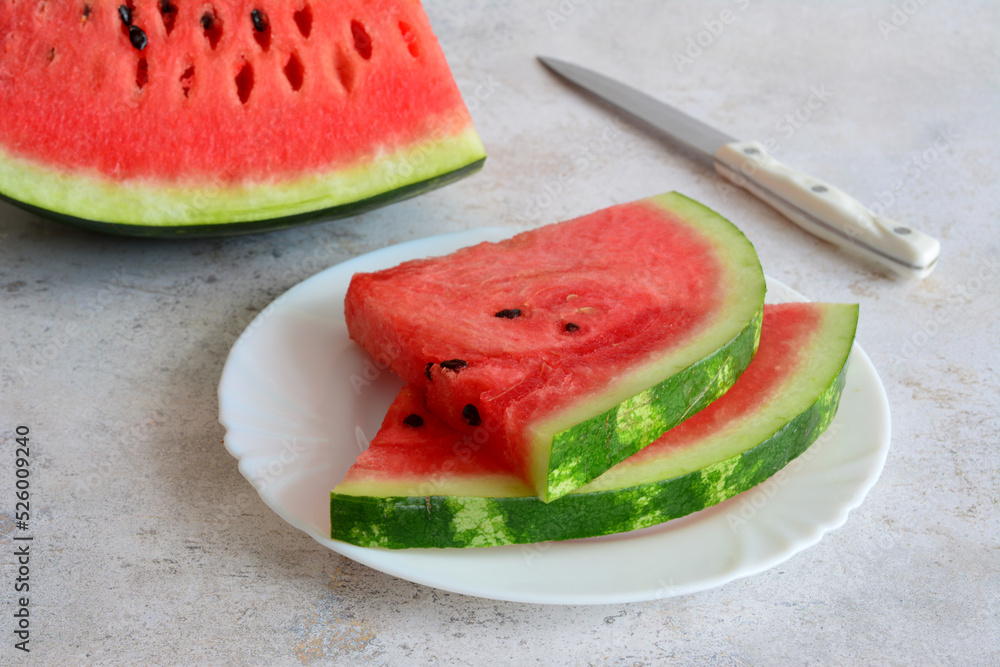 watermelon slices on white plate with kitchen knife, close-up