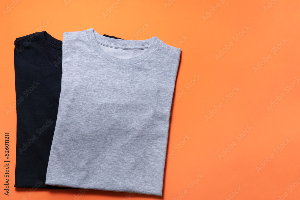 close up of rolled t shirt clothes on orange table background, travel lifestyle concept - obrazy, fototapety, plakaty 