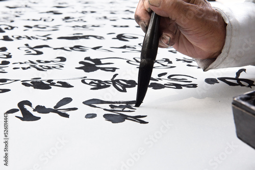 Photography a man is practicing callingraphy using a brush pen on white paper