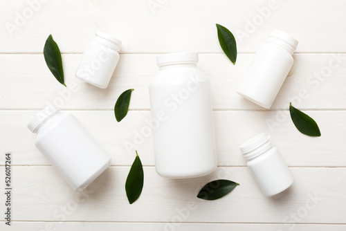 supplement pills with medicine bottle health care and medical top view. Vitamin tablets. Top view mockup bottle for pills and vitamins with green leaves, natural organic bio supplement, copy space