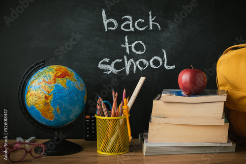 Φωτογραφία School supplies next to the globe and stack of books on the blackboard background