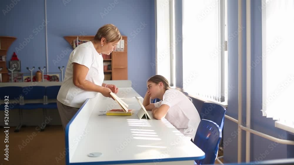 teacher explains lesson to student in one-on-one class. helping teenage child at school. girl studies on tablet teacher explains lesson to student in one-on-one class. helping teenage child at school. girl studies on tablet