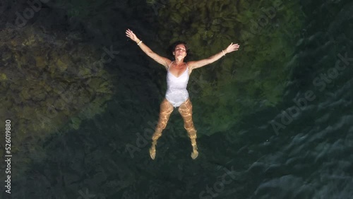 Wallpaper Mural Woman floating sea. Aerial top view of young pretty woman in white swimsuit floating on water surface in crystal clear turquoise sea. Vacation at Paradise. Ocean relax, travel and vacation. Torontodigital.ca