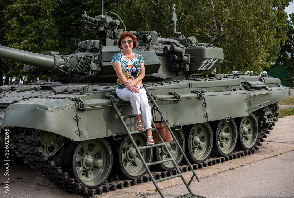 a woman against the background of a demonstration combat army tank
