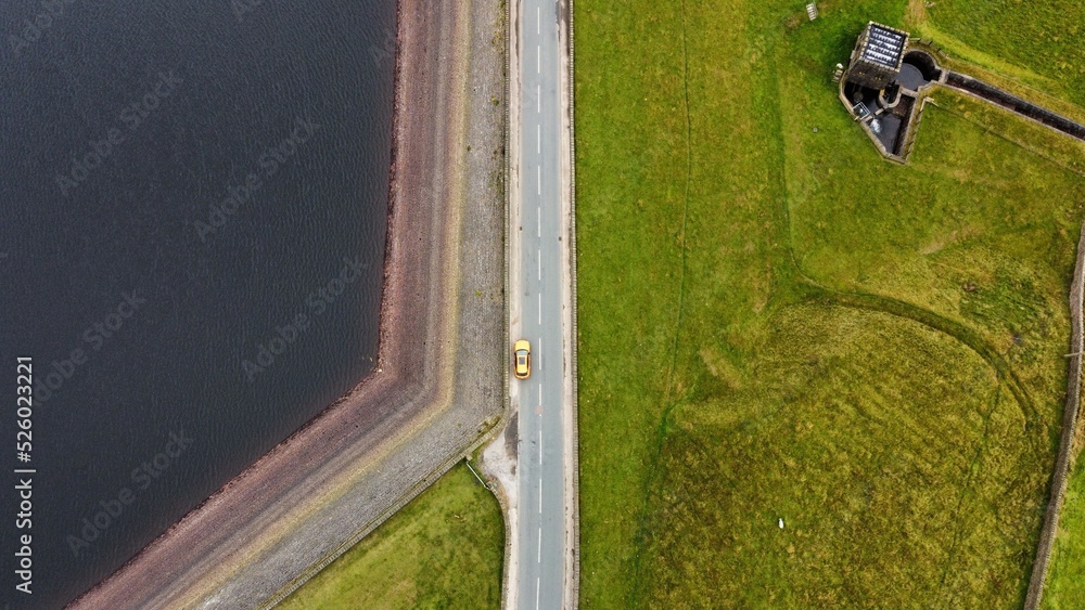 Obraz premium Aerial view of a modern car parked up on a road surrounded by countryside. 