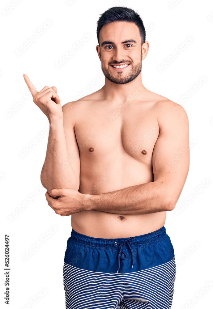 Young handsome man wearing swimwear smiling happy pointing with hand and finger to the side Young handsome man wearing swimwear smiling happy pointing with hand and finger to the side