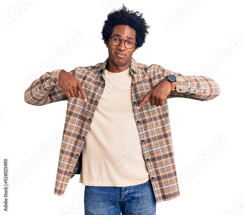 Handsome african american man with afro hair wearing casual clothes and glasses pointing down looking sad and upset, indicating direction with fingers, unhappy and depressed.