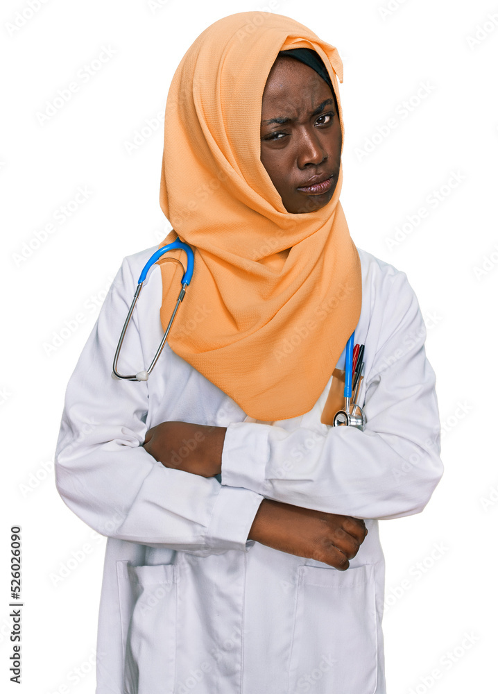 Beautiful african young woman wearing doctor uniform and hijab skeptic and nervous, disapproving expression on face with crossed arms. negative person.