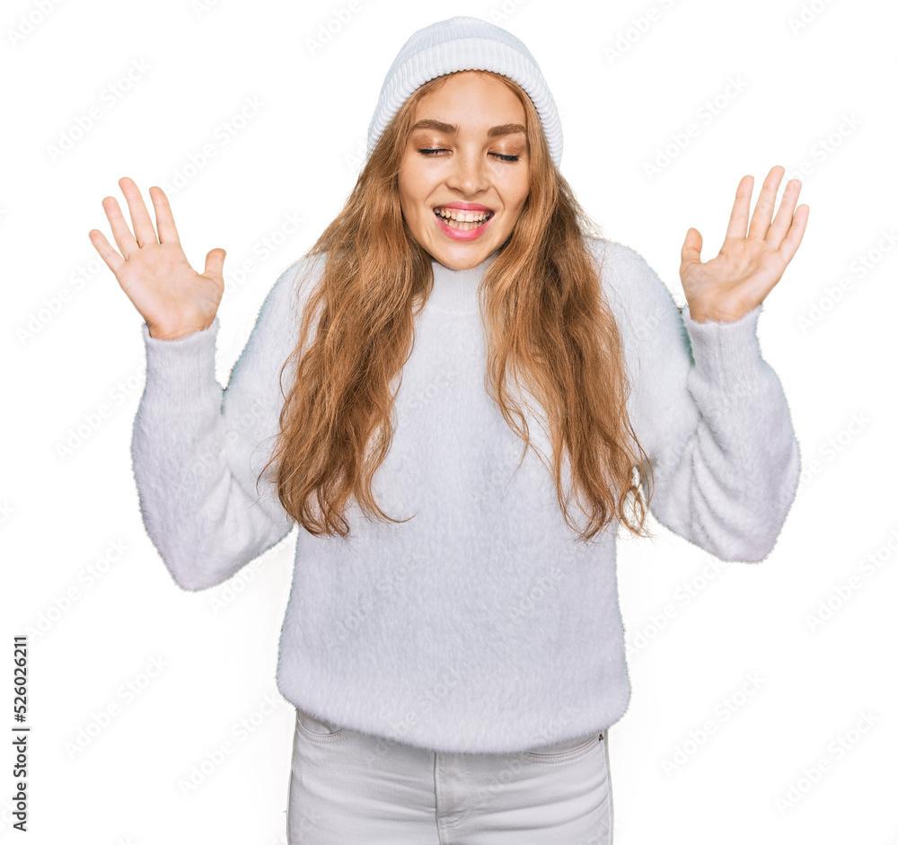 Young caucasian girl wearing wool sweater and winter cap celebrating mad and crazy for success with arms raised and closed eyes screaming excited. winner concept Young caucasian girl wearing wool sweater and winter cap celebrating mad and crazy for success with arms raised and closed eyes screaming excited. winner concept