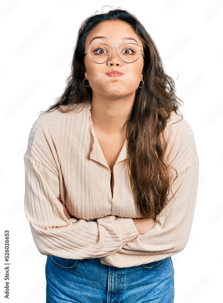 Obraz premium Young hispanic girl wearing casual clothes and glasses puffing cheeks with funny face. mouth inflated with air, catching air.
