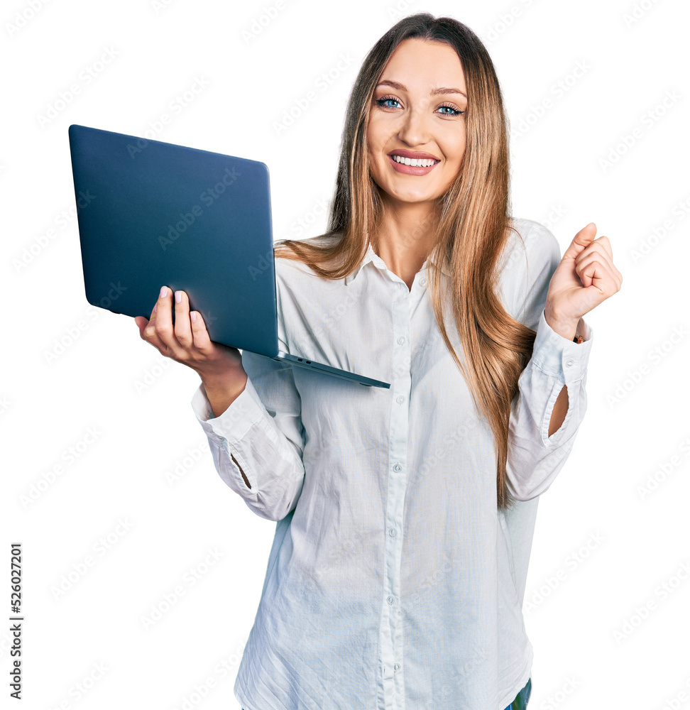 Beautiful caucasian woman working using computer laptop screaming proud, celebrating victory and success very excited with raised arm Beautiful caucasian woman working using computer laptop screaming proud, celebrating victory and success very excited with raised arm