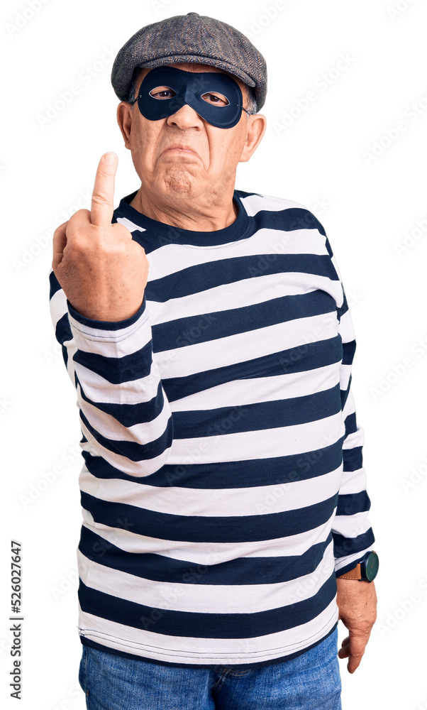 Senior handsome man wearing burglar mask and t-shirt showing middle finger, impolite and rude fuck off expression Senior handsome man wearing burglar mask and t-shirt showing middle finger, impolite and rude fuck off expression
