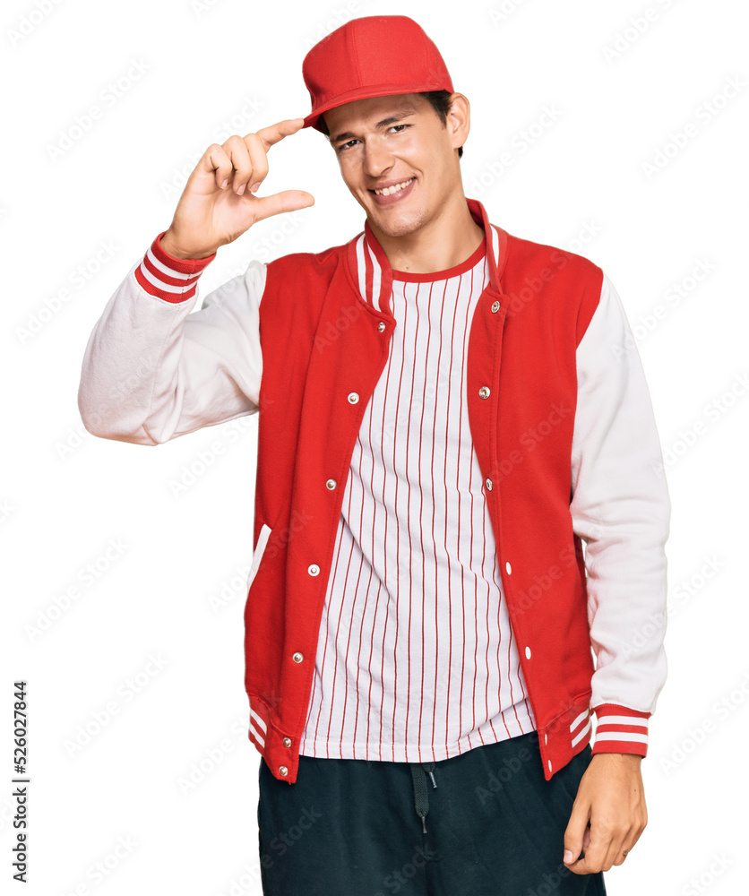 Handsome caucasian man wearing baseball uniform smiling and confident gesturing with hand doing small size sign with fingers looking and the camera. measure concept. Handsome caucasian man wearing baseball uniform smiling and confident gesturing with hand doing small size sign with fingers looking and the camera. measure concept.