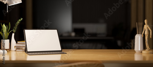 Digital tablet mockup and copy space on wooden tabletop over the dark office in background