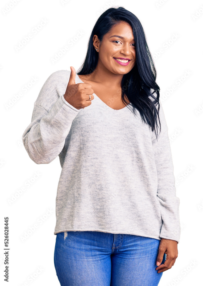 Hispanic woman with long hair wearing casual clothes doing happy thumbs up gesture with hand. approving expression looking at the camera showing success. Hispanic woman with long hair wearing casual clothes doing happy thumbs up gesture with hand. approving expression looking at the camera showing success.