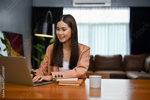 Attractive Asian businesswoman is working on her business task, using laptop computer in office.