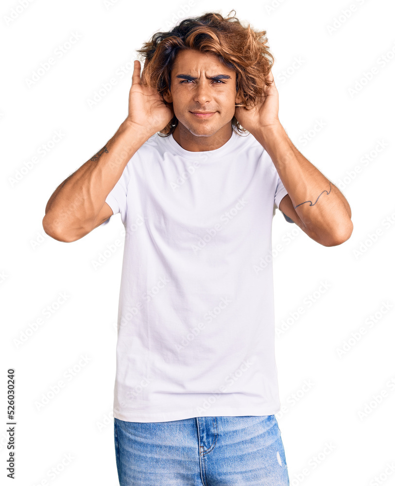 Young hispanic man wearing casual white tshirt trying to hear both hands on ear gesture, curious for gossip. hearing problem, deaf Young hispanic man wearing casual white tshirt trying to hear both hands on ear gesture, curious for gossip. hearing problem, deaf