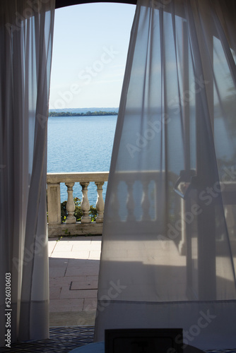 View of Lake Garda in Italy with Antique railing and flowing curtain in foreground