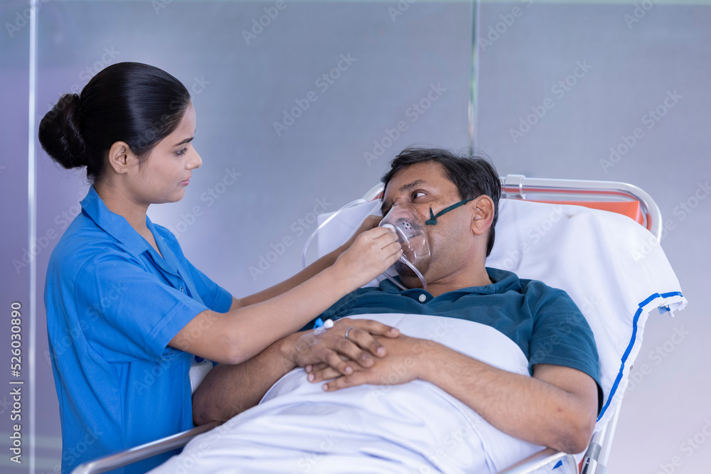 Nurse adjusting a positive pressure oxygen mask on a woman patient lying in bed on a hospital Nurse adjusting a positive pressure oxygen mask on a woman patient lying in bed on a hospital