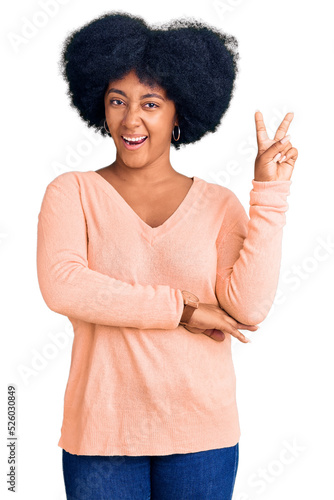 Young african american girl wearing casual clothes smiling with happy face winking at the camera doing victory sign. number two.