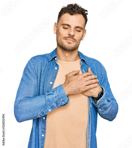 Young hispanic man wearing casual clothes smiling with hands on chest with closed eyes and grateful gesture on face. health concept.