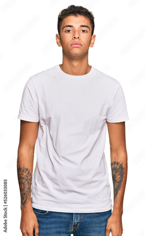 Obraz premium Young handsome african american man wearing casual white tshirt relaxed with serious expression on face. simple and natural looking at the camera.
