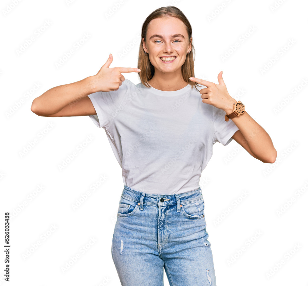 Beautiful young blonde woman wearing casual white t shirt smiling cheerful showing and pointing with fingers teeth and mouth. dental health concept. Beautiful young blonde woman wearing casual white t shirt smiling cheerful showing and pointing with fingers teeth and mouth. dental health concept.