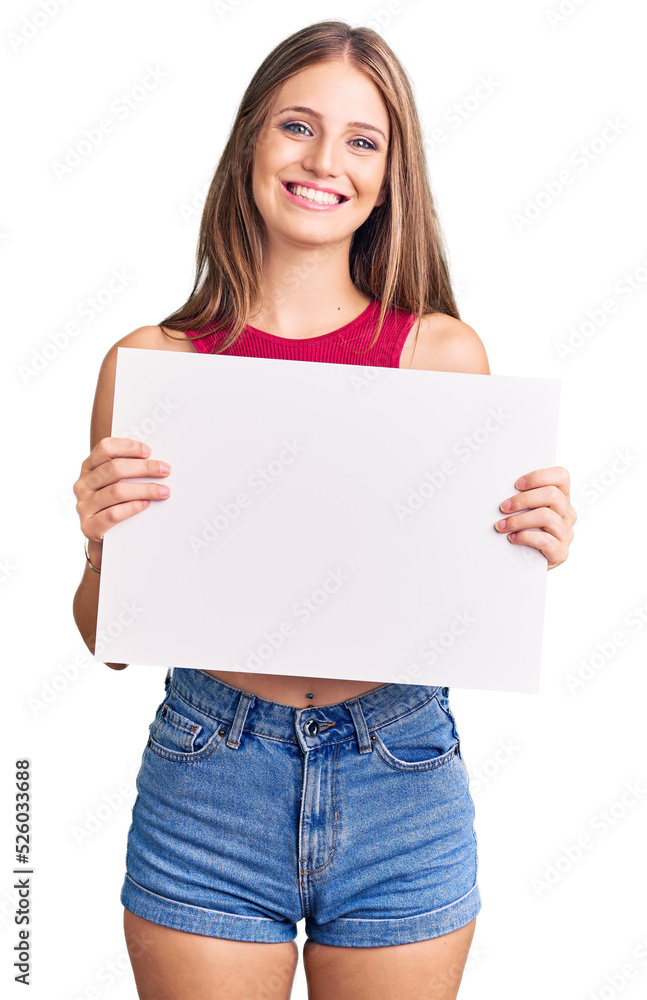 Young beautiful blonde woman holding blank empty banner looking positive and happy standing and smiling with a confident smile showing teeth Young beautiful blonde woman holding blank empty banner looking positive and happy standing and smiling with a confident smile showing teeth