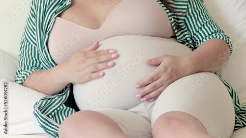 pregnant woman lies on bed caressing belly touching with palms playing with baby in uterus.advanced pregnancy female hold 3d ultrasound scan while caress the belly.maternity awaiting future mother 