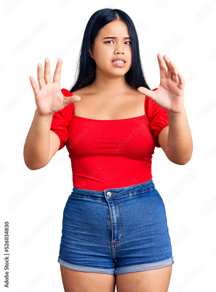 Young beautiful asian girl wearing casual clothes afraid and terrified with fear expression stop gesture with hands, shouting in shock. panic concept.