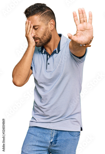 Handsome man with beard wearing casual clothes covering eyes with hands and doing stop gesture with sad and fear expression. embarrassed and negative concept.