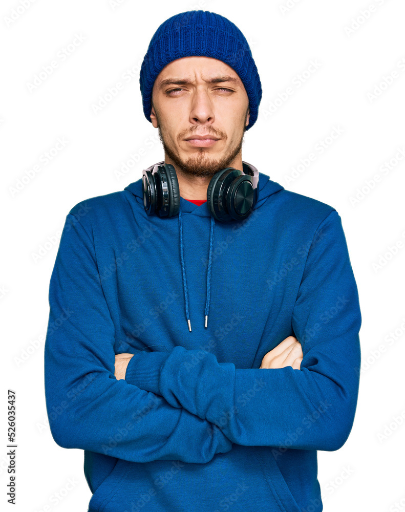 Hispanic young man wearing sweatshirt and wool hat skeptic and nervous, disapproving expression on face with crossed arms. negative person. Hispanic young man wearing sweatshirt and wool hat skeptic and nervous, disapproving expression on face with crossed arms. negative person.