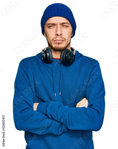 Hispanic young man wearing sweatshirt and wool hat skeptic and nervous, disapproving expression on face with crossed arms. negative person.