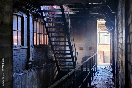 Metallic ladder in a dilapidated and half-dark dirty factory with stone walls
