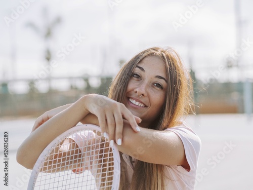 Portrait of a Hispanic female smiling and posing with a tennis racket photo