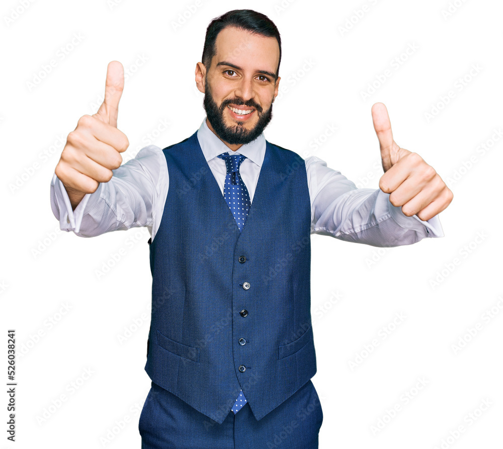 Young man with beard wearing business vest approving doing positive gesture with hand, thumbs up smiling and happy for success. winner gesture. Young man with beard wearing business vest approving doing positive gesture with hand, thumbs up smiling and happy for success. winner gesture.