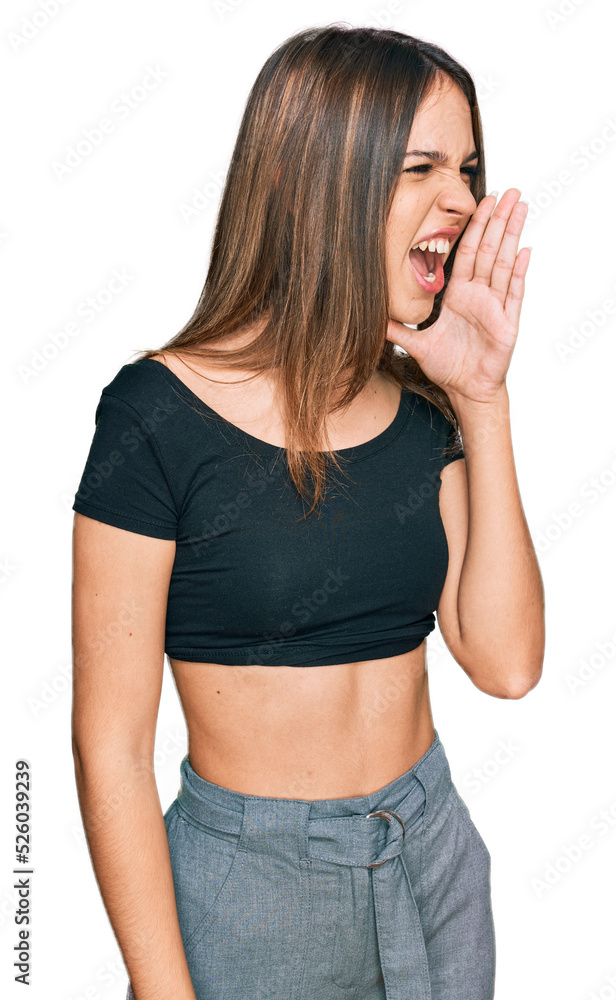 Young brunette woman wearing casual clothes shouting and screaming loud to side with hand on mouth. communication concept. Young brunette woman wearing casual clothes shouting and screaming loud to side with hand on mouth. communication concept.