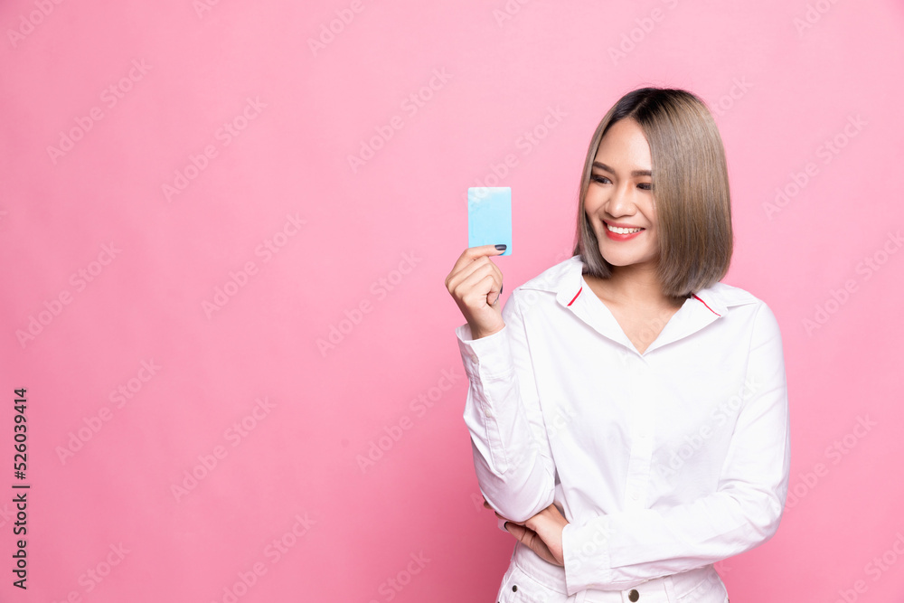 Shopping concept. Young Asian woman smiling and showing plastic credit card, paying contactless, standing over pink background Shopping concept. Young Asian woman smiling and showing plastic credit card, paying contactless, standing over pink background